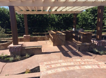 picture of a concrete patio area with concrete countertop installed as well as pillars that hold up a patio cover
